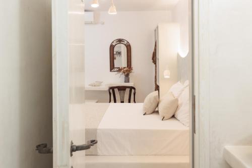 a white room with a bed and a table at Burgos Barrio Naxos in Naxos Chora