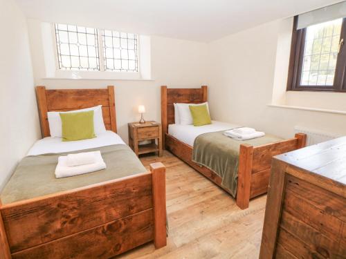 Un dormitorio con dos camas y una mesa y dos ventanas. en Andlestone, en Matlock