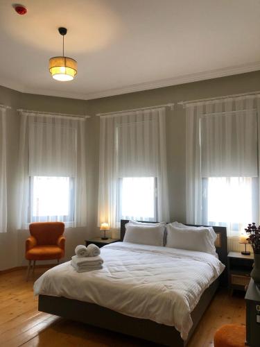 a bedroom with a bed with white sheets and windows at Utopia Konak Otel in Bozuyuk