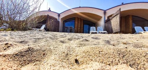 una casa sulla spiaggia con sedie nella sabbia di LAGOVIDA Dünenhaus Comfort Familia b am Störmthaler See a Grosspösna