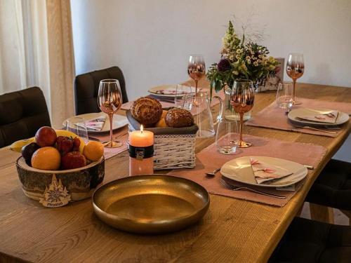 普夫龙滕Ferienwohnung Breitenbergblick - Haus Alpentenne, Pfronten的一张木桌,上面放着一碗水果和酒杯