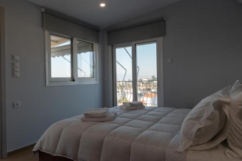 a bedroom with a large bed with two windows at Etherial Comfy House 2 in Kalamata