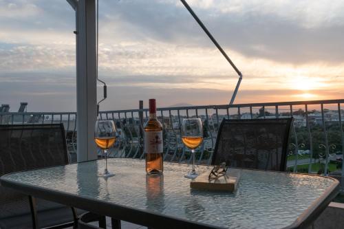 a bottle of wine sitting on a table with two wine glasses at Etherial Comfy House 2 in Kalamata