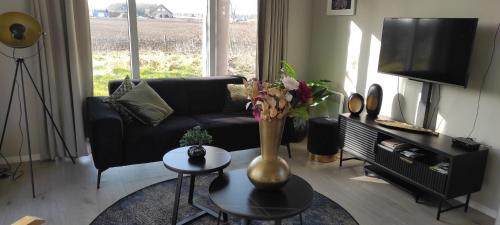 a living room with a couch and a vase with flowers on a table at Casa Bosrust - Luxe, rust, natuur en privacy in Haarle
