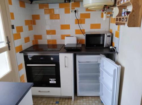 une petite cuisine avec une cuisinière et un micro-ondes dans l'établissement Appartement entier de 40 m2 proche gare Auterive, à Auterive