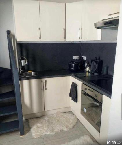 une cuisine avec des armoires blanches et un comptoir noir dans l'établissement Appartement en attique Strasbourg ville proche gare Halles, à Strasbourg