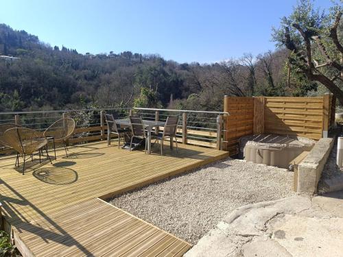 una terrazza in legno con tavolo e sedie. di Bas de Villa avec entrée indépendante en pleine nature a Le Bar-sur-Loup