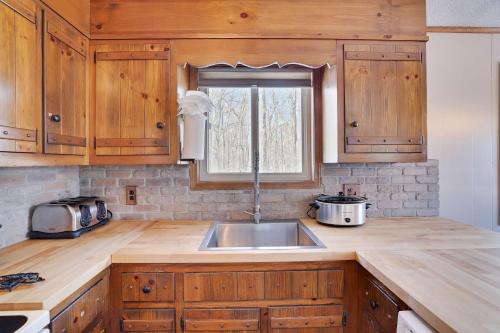 a kitchen with wooden cabinets and a sink and a window at 4 Br Cozy Cabin Sleeps 8 Pool Table Arcade Beach in Gouldsboro