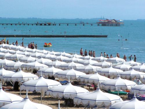 a bunch of white umbrellas on a beach at Hotel Bellevue in Lignano Sabbiadoro