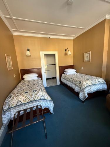 a hotel room with two beds and a doorway at The Inn at Cooperstown in Cooperstown