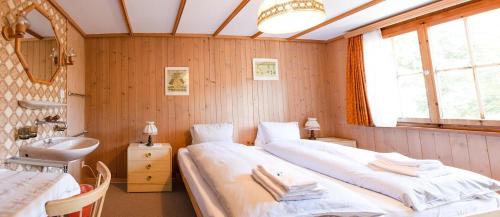 a bedroom with two beds and a sink and a mirror at Chalet Suveran 2 in Arosa