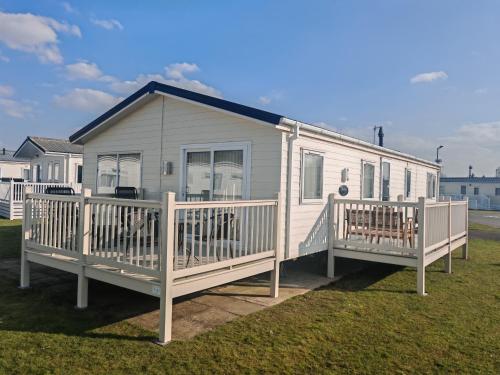 a white house with a porch and a deck at Manor Park Dog Friendly 2 bed, 6 berth Lodge with decking 600 Yard's From The Beach In Hunstanton in New Hunstanton