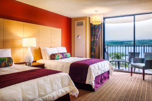 a hotel room with two beds and a balcony at Hilo Hawaiian Hotel, Trademark Collection by Wyndham in Hilo