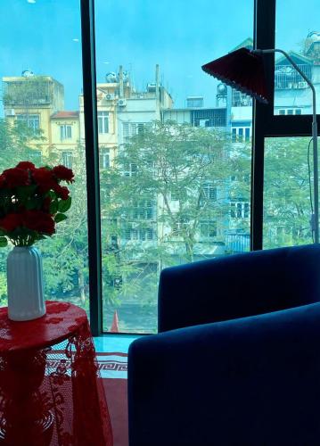 a vase of flowers on a table in front of a window at The Grand Diamond C Tuong Mai in Hanoi