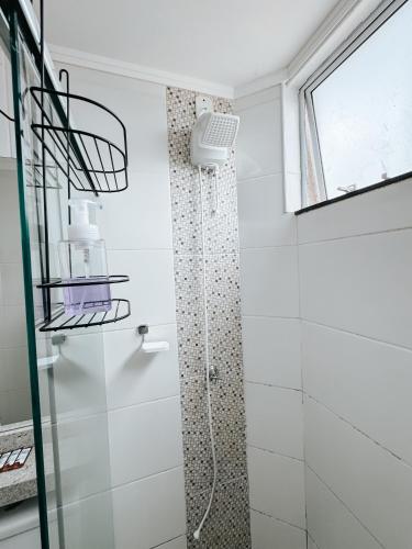 a shower in a white bathroom with a glass door at Novo Apto em Condomínio Fechado c/Ar e Elevador in Três Lagoas