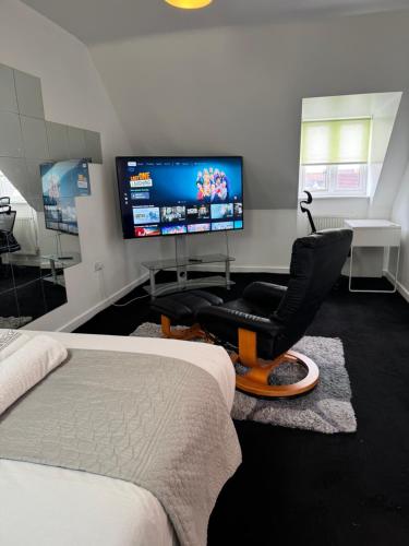 a bedroom with a bed and a chair and a flat screen tv at Home Away from Home in Milton Keynes