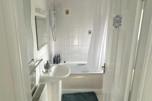 une salle de bain blanche avec une baignoire et un lavabo dans l'établissement Cosy 3-Bed Retreat - Garden Parking & Bbq, à Birmingham