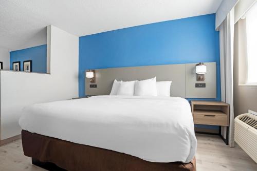 a large white bed in a room with a blue wall at Comfort Inn & Suites Crystal Inn Sportsplex in Gulfport
