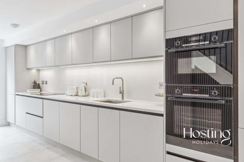 a kitchen with white cabinets and a stove top oven at Queens Mews Brand New Luxury Home with Parking in Henley on Thames
