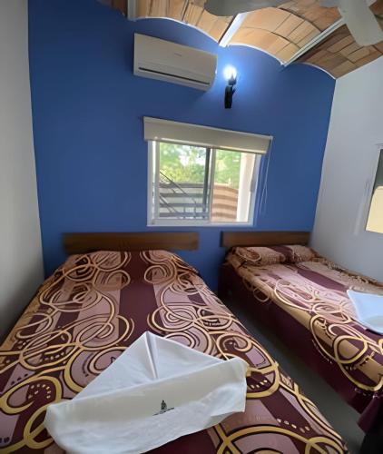 a blue room with two beds and a window at C4 Alberca privada a 5 min de la playa planta alta in Peñita de Jaltemba