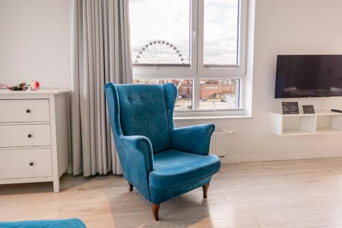 a blue chair in a living room with a window at Chrobry Apartamenty Gdańsk Grodzka 10 in Gdańsk