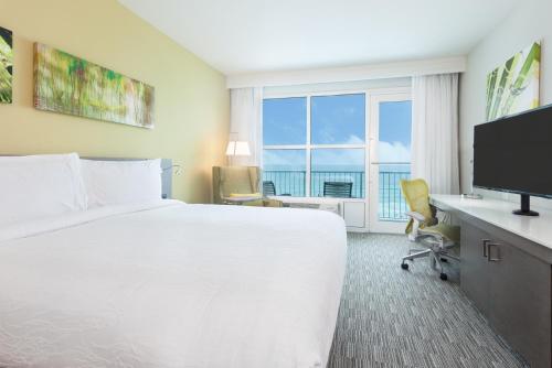 a hotel room with a bed and a desk with a television at Hilton Garden Inn Ft. Walton Beach in Fort Walton Beach