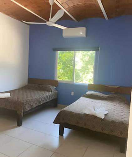 a bedroom with two beds and a ceiling fan at C7 Casas la colmena a 3 min playa alberca 4 rec, in Peñita de Jaltemba