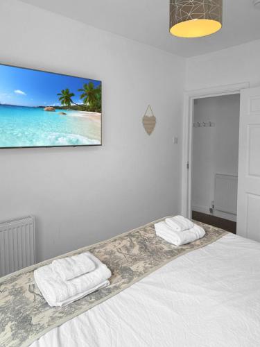 a white bedroom with a bed with two towels on it at Granada Apartments Queen's Promenade in Blackpool