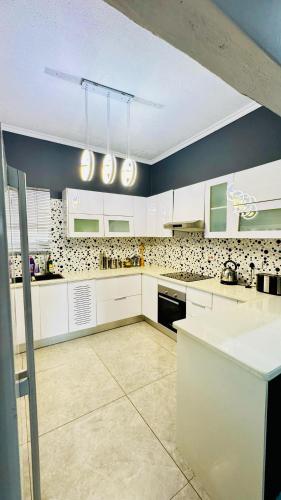 a large kitchen with white cabinets and appliances at CBD sanctuary-self catering in Gaborone
