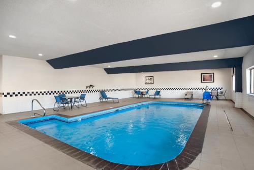 a pool in a hotel with blue chairs and a table at Comfort Inn & Suites Crystal Inn Sportsplex in Gulfport