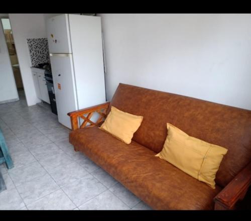 a brown couch with two yellow pillows on it at Dptos Reynoso in Villa Mercedes