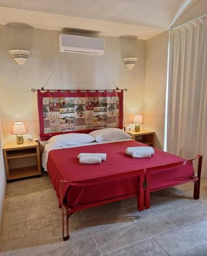 a bedroom with a red bed with two towels on it at Masseria Le Celline in Nardò