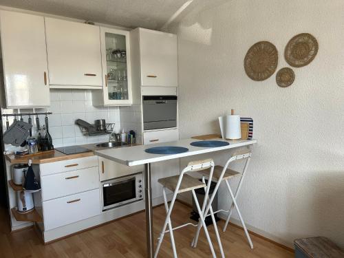 une cuisine avec des placards blancs et un comptoir avec deux tabourets dans l'établissement Studio - Calais la Plage, à Calais