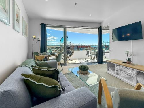 a living room with a couch and a table at Le Mirage- Stylish, central apartment with pools, sauna, more in Auckland