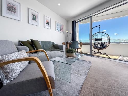 a living room with a couch and a glass table at Le Mirage- Stylish, central apartment with pools, sauna, more in Auckland