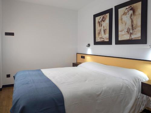 a bedroom with a bed with two pictures on the wall at Hotel Apartamento Marouco in A Guarda