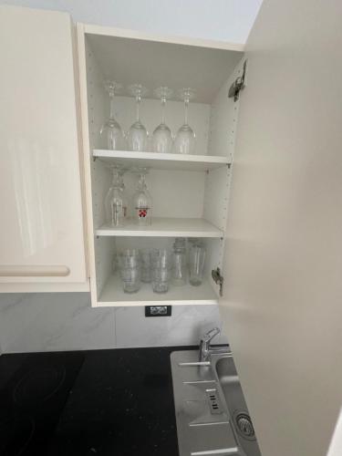 a kitchen cabinet with glass jars and a sink at Apartments Funtana with pool in Funtana
