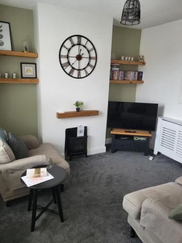 a living room with a large clock on the wall at Rugby town centre house close to train station, rugby school and benn hall in Rugby