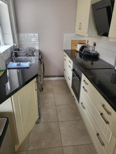 a kitchen with black counter tops and a sink at Rugby town centre house close to train station, rugby school and benn hall in Rugby