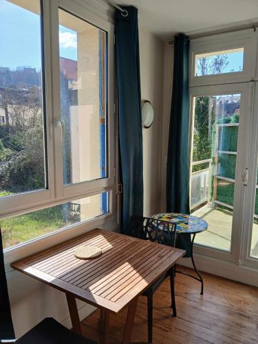 Cette chambre dispose d'une table en bois et d'une grande fenêtre. dans l'établissement Voiles et Terrasses by Corinne Résidence face au port, au Tréport