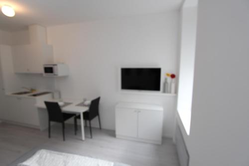 a white kitchen with a table and a tv on a wall at Apartments Simple Teslina in Zagreb