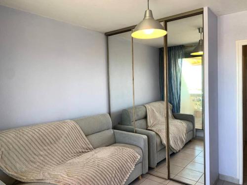 un salon avec un canapé et un miroir dans l'établissement Résidence Héliopolis Bâtiment Ab - Studio pour 2 Personnes 454, au Cap d'Agde