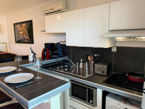 une cuisine avec des placards blancs et un comptoir avec des verres à vin dans l'établissement Résidence Port Soleil Bâtiment B2 - Studio 2 Personnes - Port Soleil MAE-4431, au Cap d'Agde