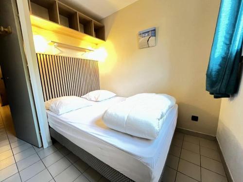 un lit avec des draps blancs et des oreillers dans une chambre dans l'établissement Résidence Le Beaulieu - Appartement 6 couchages à Port Camargue MAE-5351, au Grau-du-Roi