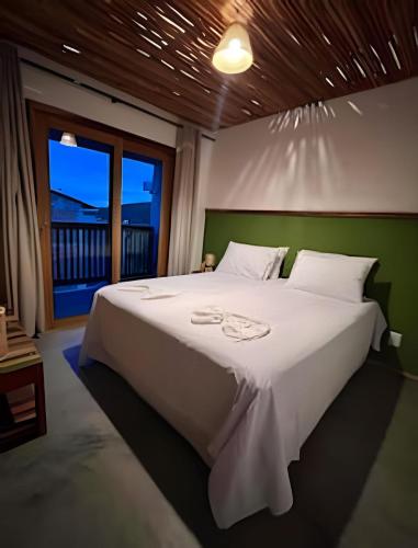 a bedroom with a large white bed and a window at Casa dos Pássaros - AR Condicionado nos dois quartos in Lençóis