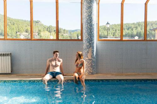 un hombre y una mujer sentados en una piscina en Hotel Xauen, en Montanejos