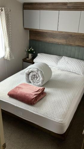 a large bed with white sheets and a pink pillow at Barmouthbay209 in Barmouth