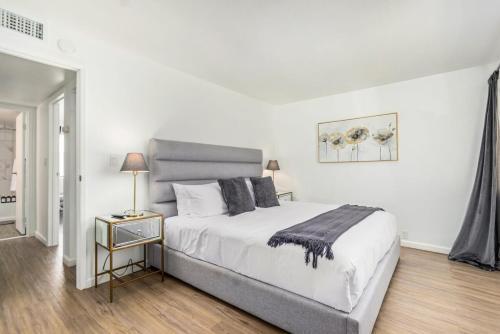 a white bedroom with a large bed and a night stand at Camelback 446 at Fashion Square in Scottsdale