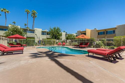 a pool with red benches and umbrellas in a courtyard at Camelback 446 at Fashion Square in Scottsdale