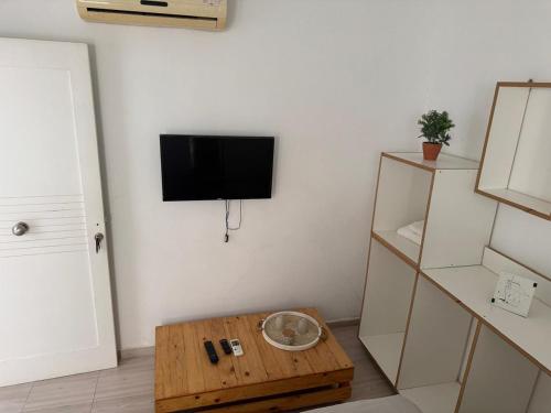 Una sala de estar con una mesa y un televisor en una pared. en Le cocon lumineux, en Sfax